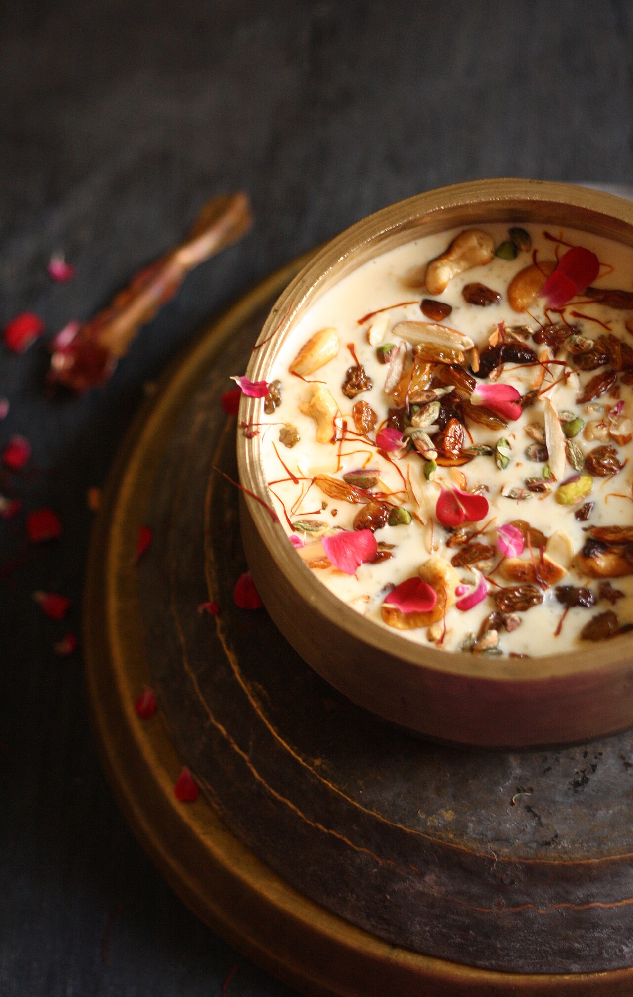 A bowl of rich kheer garnished with nuts, saffron and rose petals