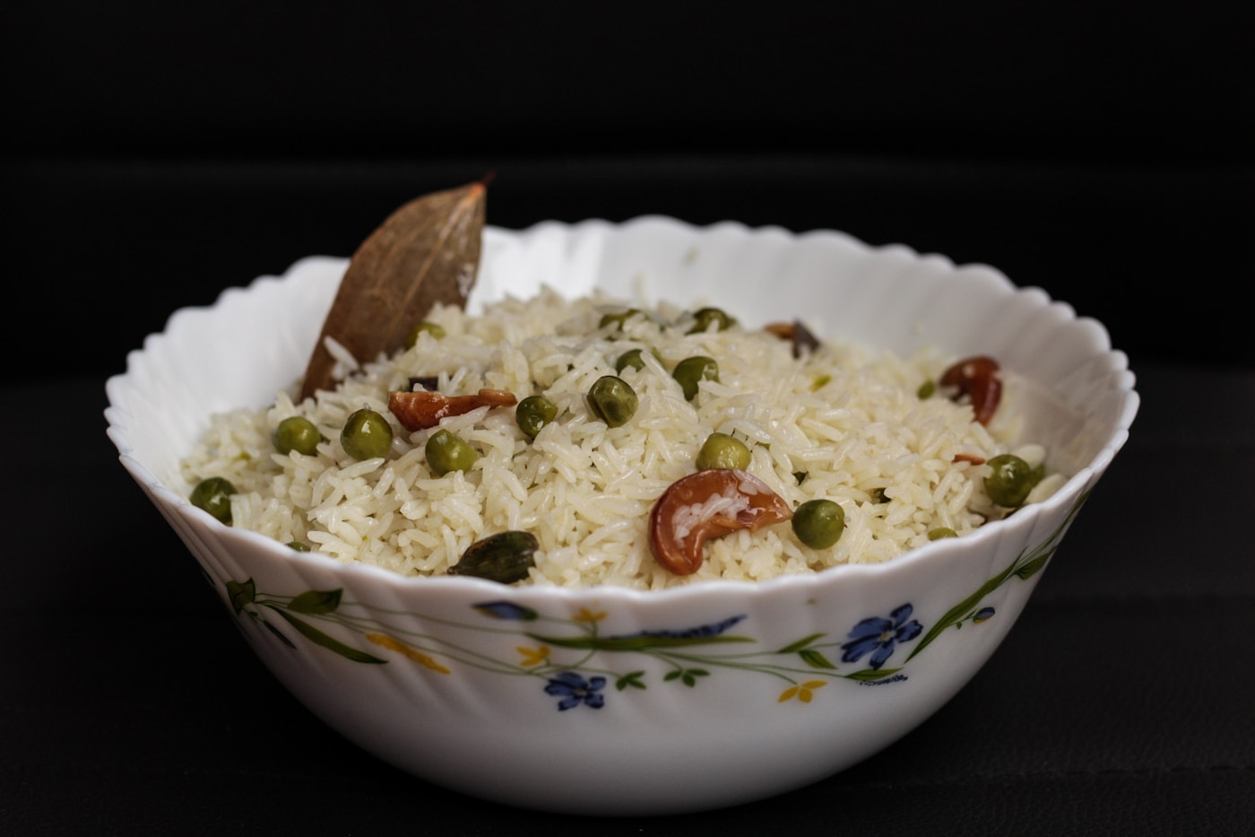 A bowl of white peas pulao with cashews and whole spices